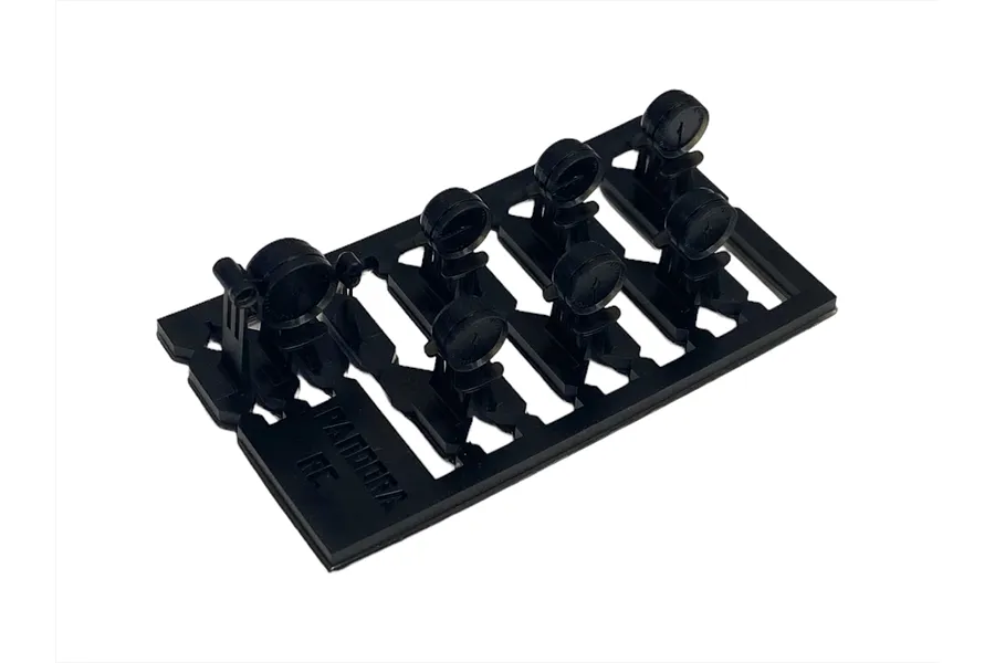 A black plastic sprue containing seven miniature gauge or meter parts for 1/10 scale RC car interior detailing by Pandora RC.