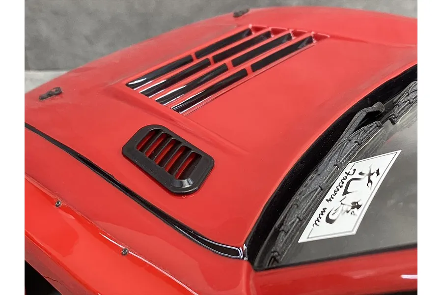 Close-up of a red RC car bonnet featuring black aftermarket air ducts and vents installed on the hood.