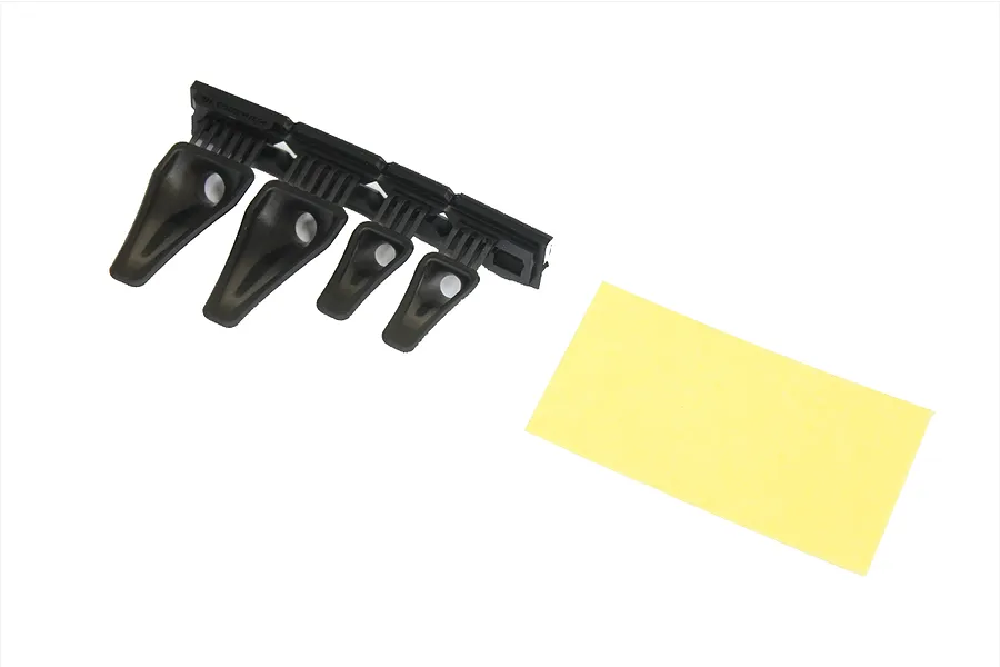 Four black plastic NACA duct parts on a sprue with a small rectangular yellow adhesive sheet on a white background.