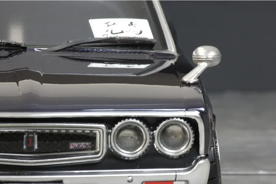Close-up of a silver fender mirror mounted on the hood of a dark-colored 1/10 scale RC car body shell.