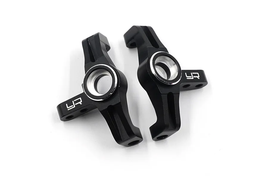 A pair of black anodized aluminium C-hub carriers for RC cars by Yeah Racing, featuring silver-edged bearing seats and the YR logo.