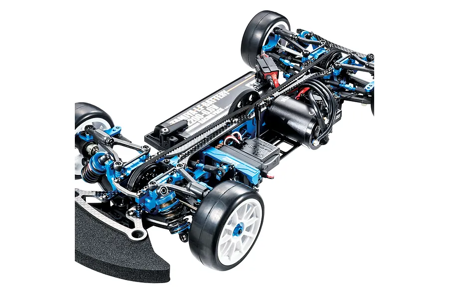 A high-angle studio shot of a Tamiya TRF421X 1/10 scale RC touring car chassis, featuring blue anodized aluminum parts, carbon fiber plates, and a Tamiya battery.
