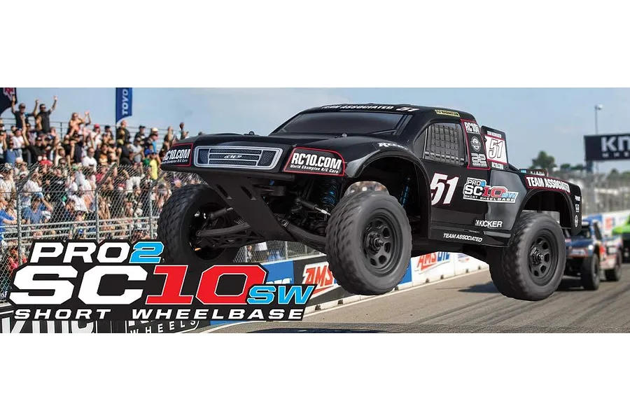 Team Associated Pro2 SC10sw RC short course truck in black jumping over a dirt track with a crowd in the background.
