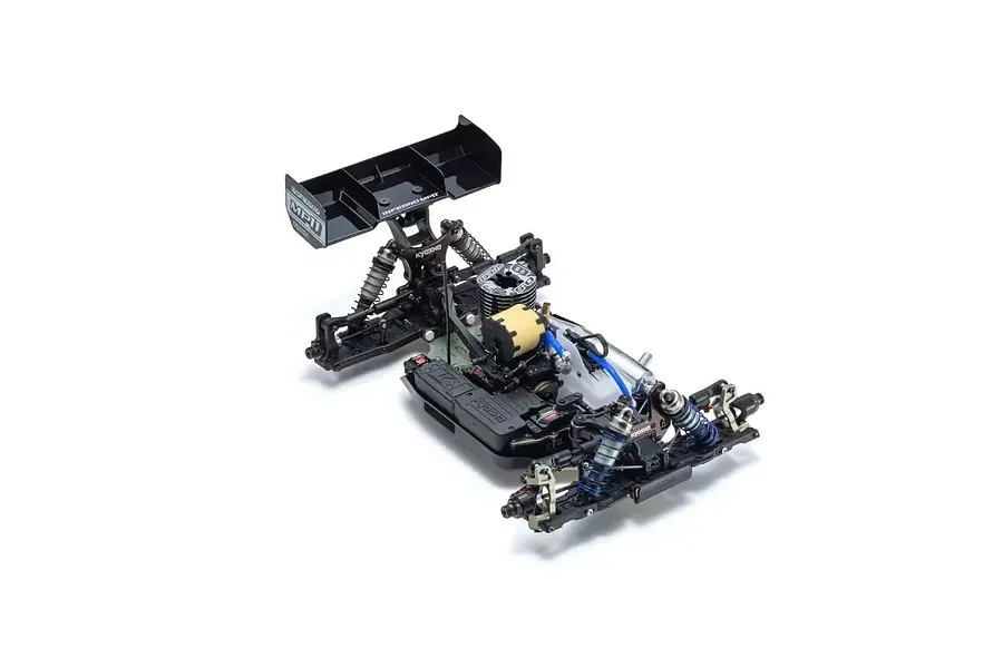 A high-angle studio shot of the Kyosho Inferno MP11 1/8 scale nitro RC buggy chassis, showing the engine, suspension, and rear wing.