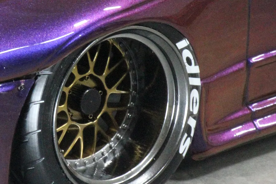 Close-up of a purple RC car wheel featuring a gold mesh rim and a black tyre with white 'idlers' lettering applied to the sidewall.