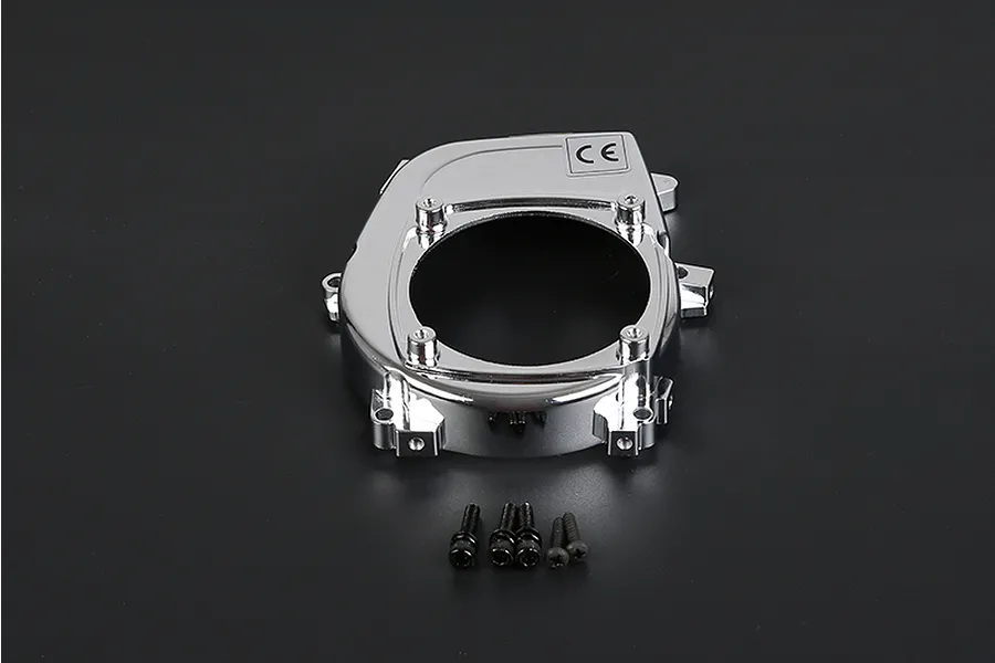 A chrome-finished Rovan RC engine cover with a central circular opening and five small black mounting screws placed below it on a dark background.