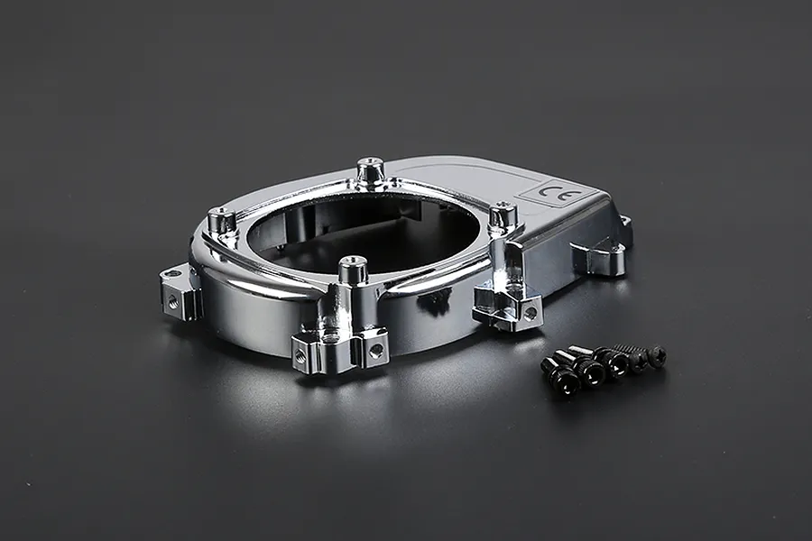 A chrome-plated Rovan engine cover for an RC car, shown with a set of small black mounting screws on a dark grey background.