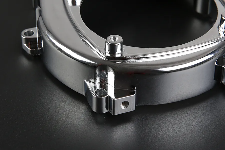 A close-up view of a shiny chrome-finished RC engine cover part against a dark background.