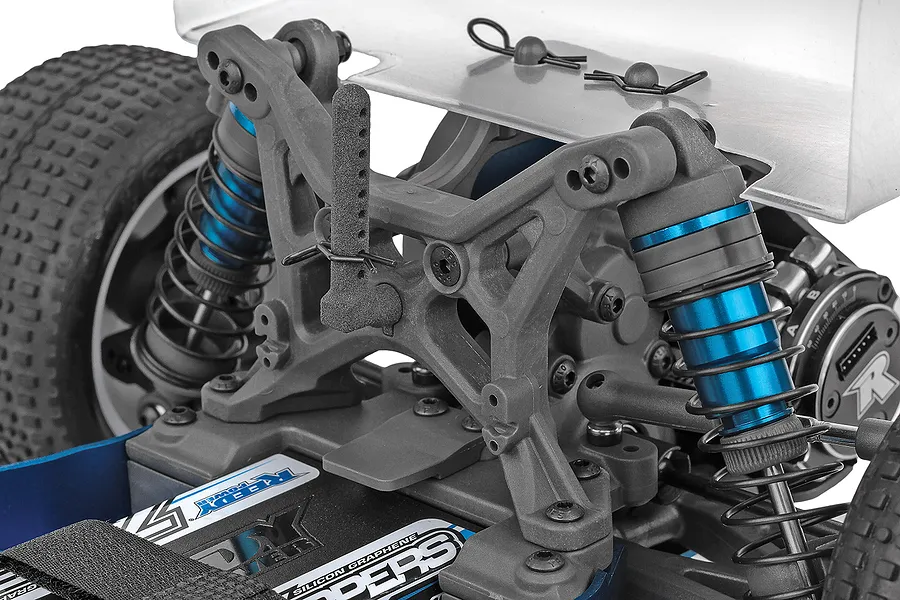 Close-up of the rear suspension and shock tower of a Team Associated RB10 RC buggy, showing blue anodized shocks and a Reedy battery pack.