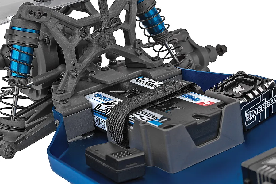 Close-up of the chassis of a Team Associated RC buggy showing the battery, blue shock absorbers, and electronic speed controller.