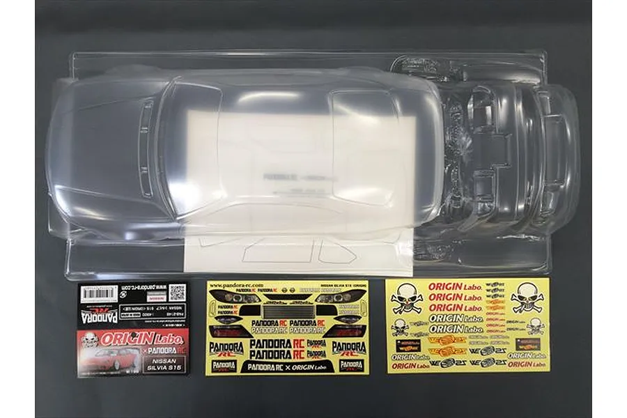 An unpainted clear polycarbonate Nissan Silvia S15 RC car body shell with decal sheets and packaging inserts on a dark background.