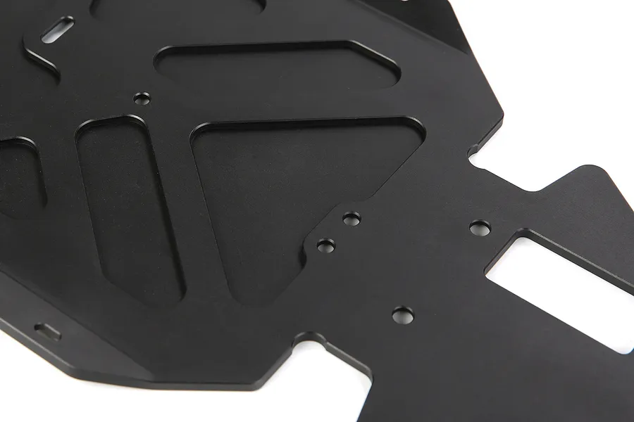 A close-up view of a black anodized aluminium RC main chassis plate with various cutouts and mounting holes.