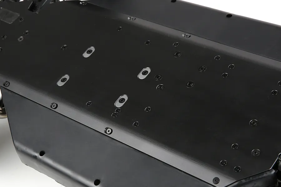 A close-up view of the black anodized aluminium main chassis plate for a Rovan LT RC vehicle, showing the underside with numerous screw holes.