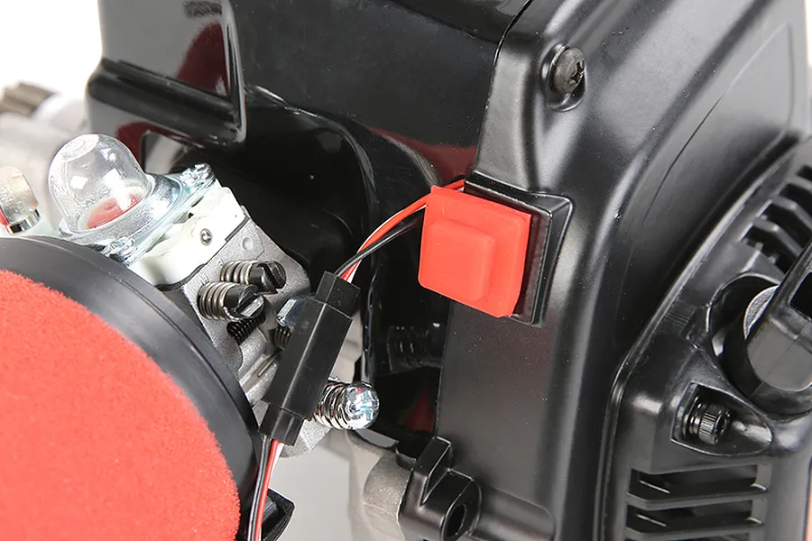 Close-up of a Rovan RC engine showing a red rubber-covered kill switch button mounted on the black plastic engine casing.