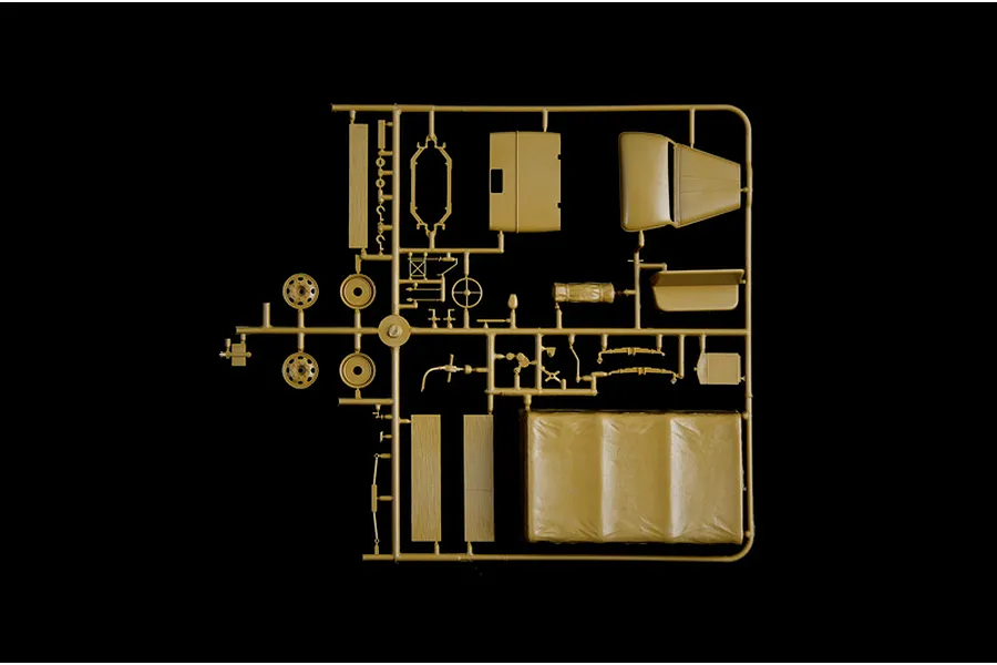 A tan plastic sprue containing various model truck parts, including wheels, a truck bed cover, and interior components, isolated on a black background.