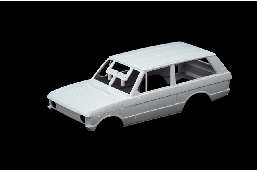 Unpainted white plastic model car body shell of a Range Rover on a black background.