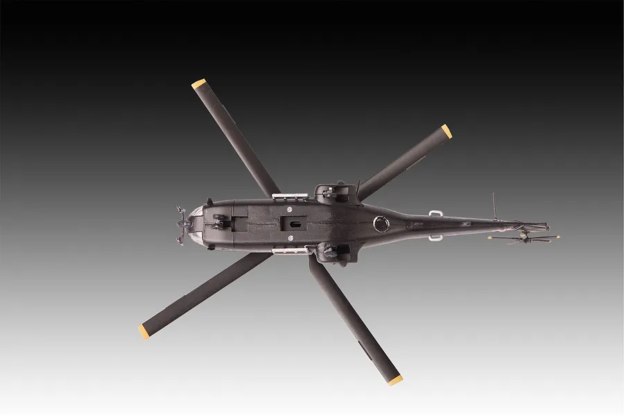 A top-down view of a 1/144 scale Westland Puma HC.1 helicopter model kit, showing the underside of the fuselage, landing gear, and rotor blades.