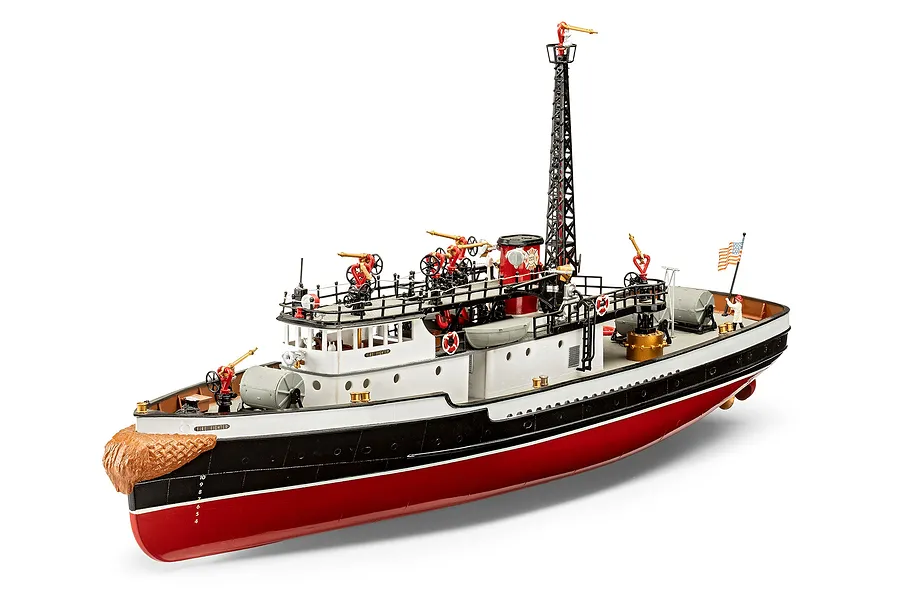 A fully assembled and painted 1/87 scale plastic model of the Fire Fighter fireboat, featuring a red hull, white superstructure, and detailed deck equipment.
