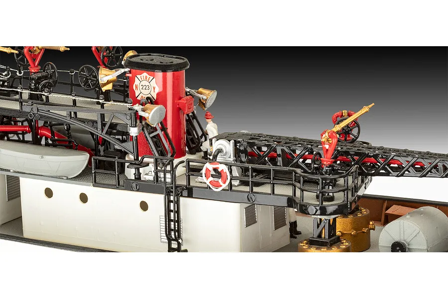 Close-up of the deck of a Revell 1/87 scale fireboat model kit showing a red funnel, railings, ladders, and miniature firefighter figures.