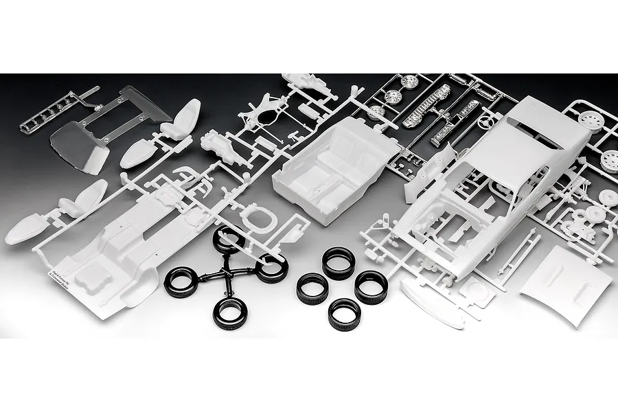 Unassembled plastic model car kit parts for a 1971 Plymouth GTX, including white body panels, interior, and black rubber tires on a black background.