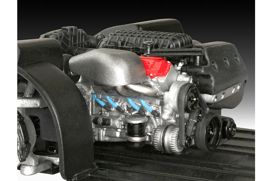 A detailed scale model of a V8 car engine, painted in silver, black, and red, mounted on a black plastic chassis base.