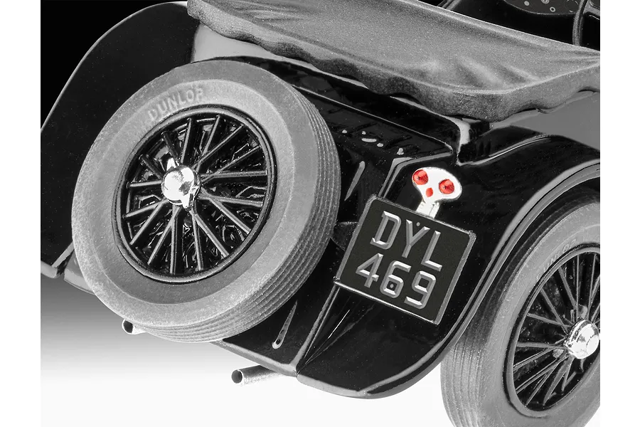 Close-up of the rear section of a black Jaguar SS 100 model car, showing the spare tire, license plate DYL 469, and red taillight.