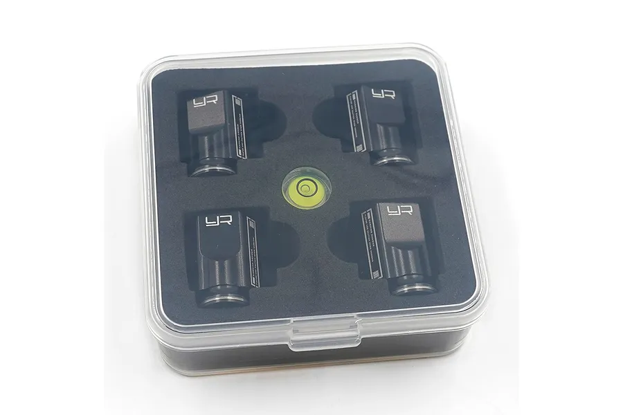 A set of four black Yeah Racing aluminium level blocks and a circular spirit level in a clear plastic storage case with black foam insert.