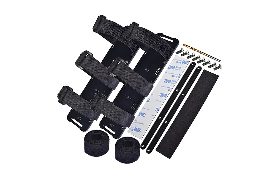 GPM Racing black aluminium battery hold-down set including plates, velcro straps, screws, adhesive tape, and a drill bit.