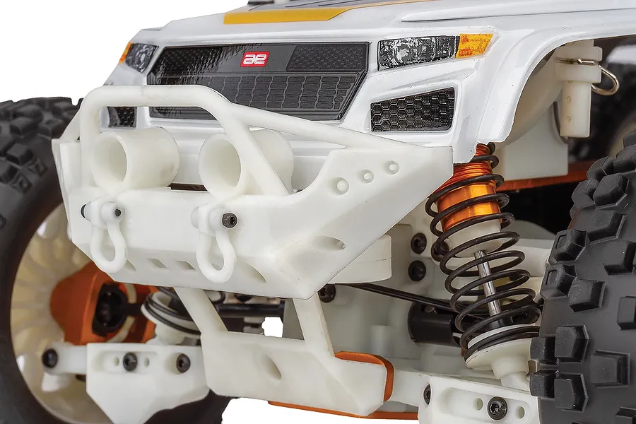 Close-up of the front end of a Team Associated Rival MT10 RC monster truck, showing the white bumper, orange shock absorbers, and black grille.