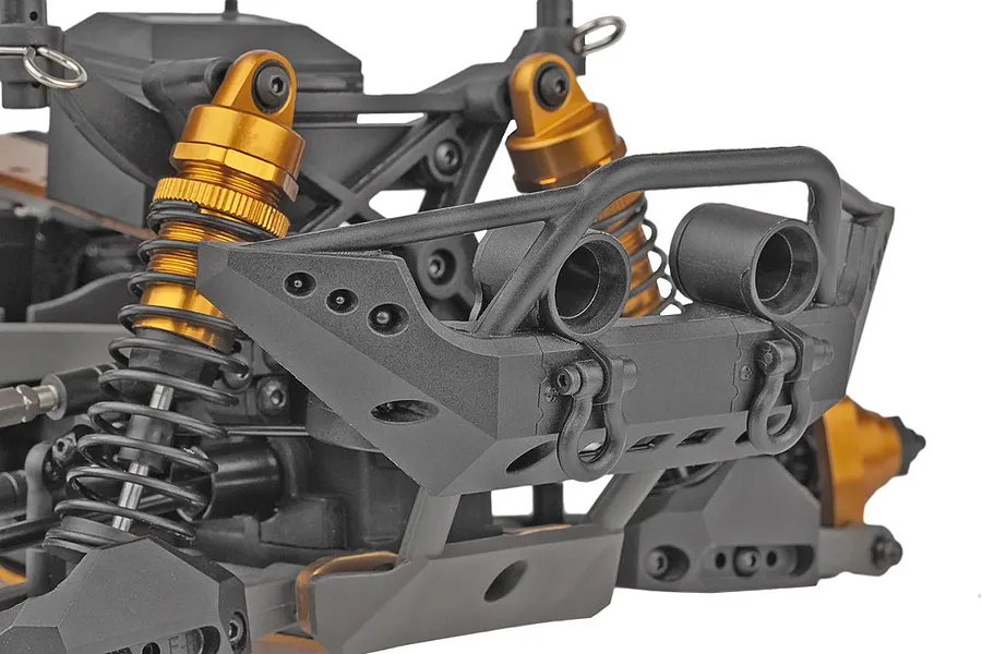 Close-up of the front bumper and suspension of a Team Associated Rival MT10 RC monster truck, featuring black plastic parts and gold-anodized shock absorbers.
