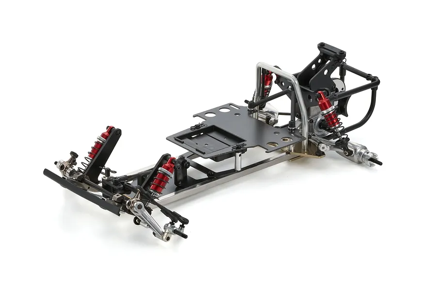 A partially assembled Kyosho Tomahawk 1/10 scale RC buggy chassis featuring a metal frame, black battery tray, and red coil-over shock absorbers.