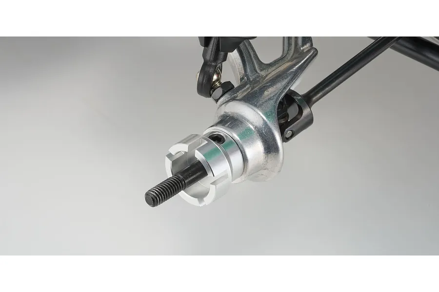 Close-up of a Kyosho RC buggy front wheel hub assembly with a metal steering knuckle and wheel hex adapter on a plain background.