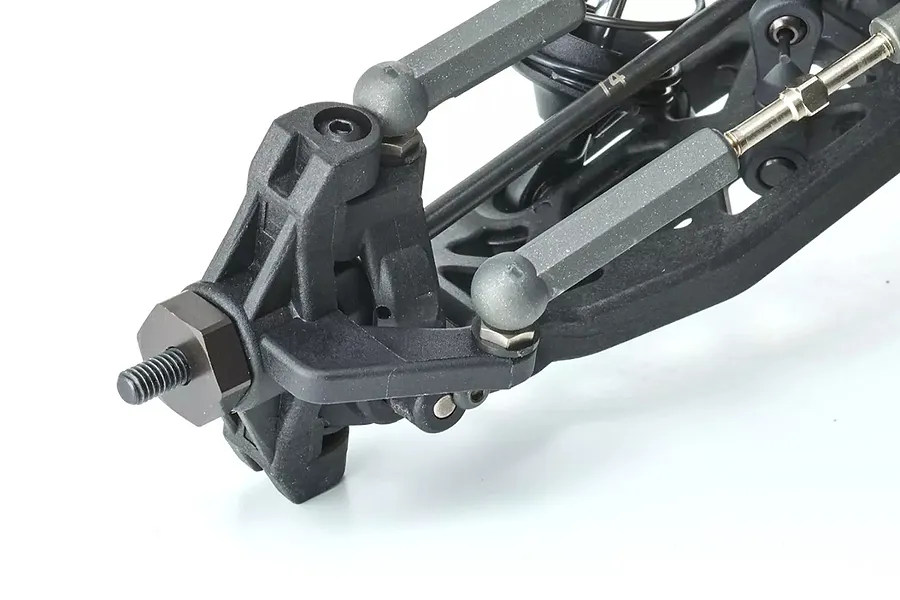 Close-up of the front suspension assembly of a 1/10 scale RC buggy, showing the steering knuckle, wheel hex, and suspension arms.