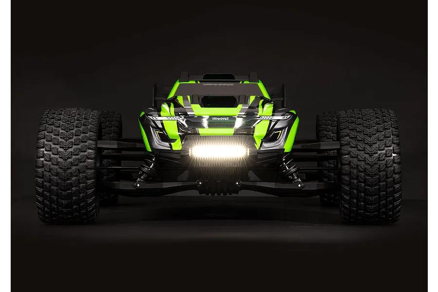 Front view of a Traxxas RC truck with a bright, illuminated double row LED light bar mounted on the front bumper against a dark background.
