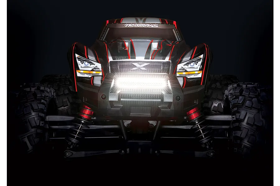 Front view of a Traxxas RC truck with a bright, illuminated double row LED light bar mounted on the front bumper against a black background.