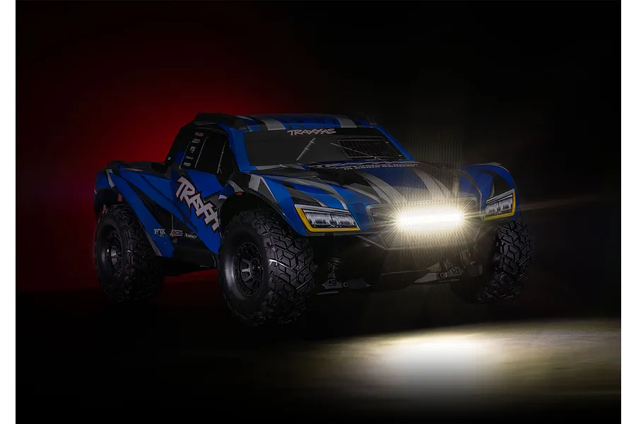 A blue Traxxas RC trophy truck with an illuminated double row LED light bar mounted on the front bumper, set against a dark background.