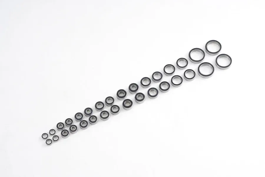 A collection of various sized metal ball bearings arranged in two rows on a plain white background.