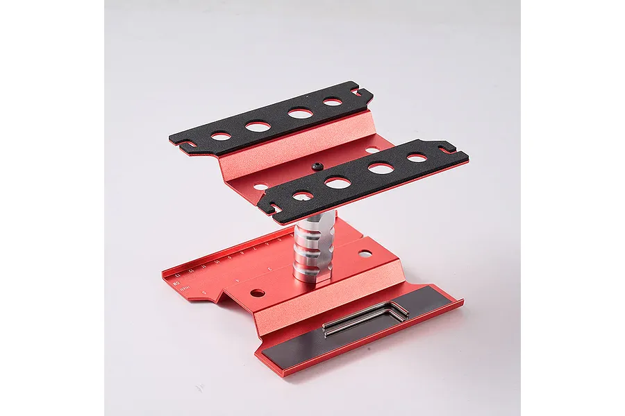 A red aluminium RC car maintenance stand with a central adjustable pillar and black foam pads on the top platform.