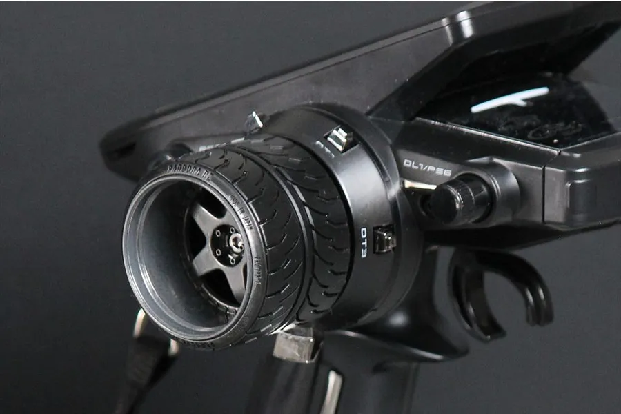 Close-up of a Pandora RC custom steering wheel installed on a Futaba RC transmitter, featuring a realistic tire tread design.