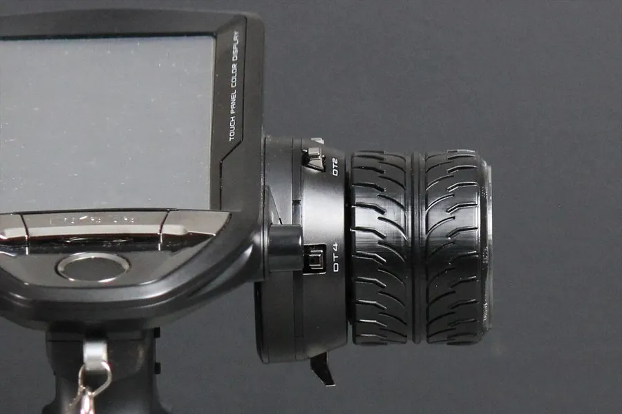 A close-up side view of a Futaba RC transmitter steering wheel modified with a Pandora RC tire-style steering wheel accessory.