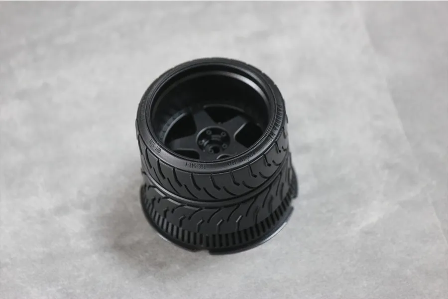 A black Pandora RC transmitter steering wheel accessory for Futaba 7PX/10PX, featuring a realistic tire tread design, viewed from above on a grey surface.