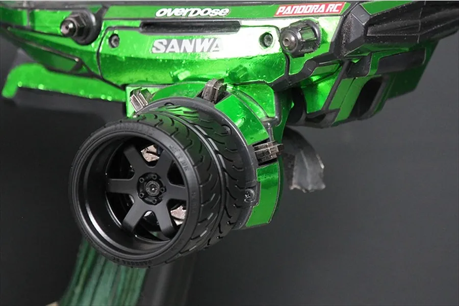 A black Pandora RC 6-spoke steering wheel accessory installed on a metallic green Sanwa RC transmitter.
