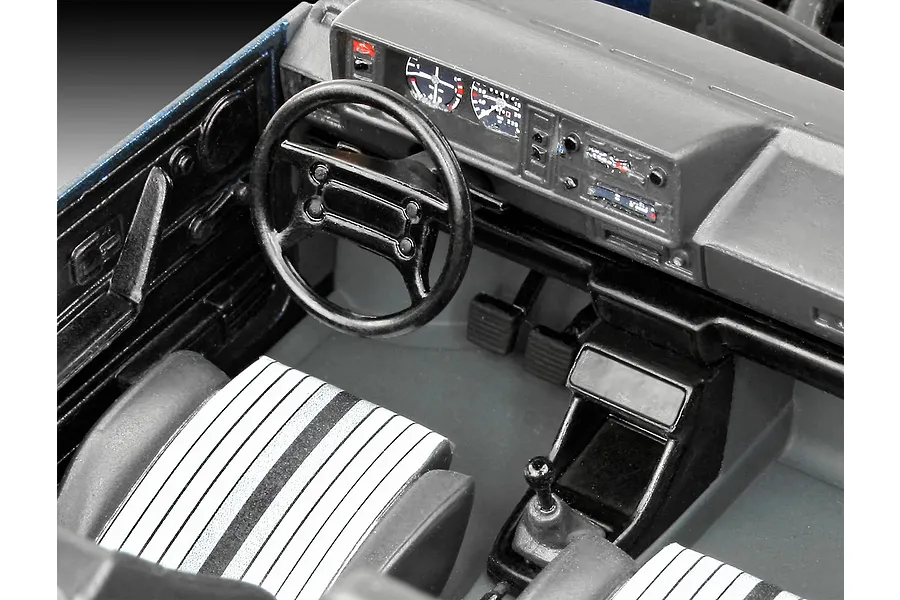 A detailed interior view of a 1/24 scale model car showing the dashboard, steering wheel, and striped seats.