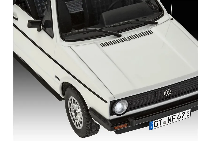 A high-angle close-up of a white 1/24 scale model VW Golf 1, showing the front hood, grille, headlights, and license plate.