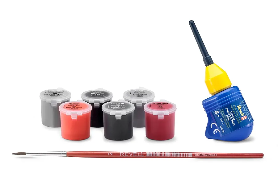Revell model kit accessories including six small paint pots, a bottle of Contacta Professional Mini glue, and a paintbrush on a white background.