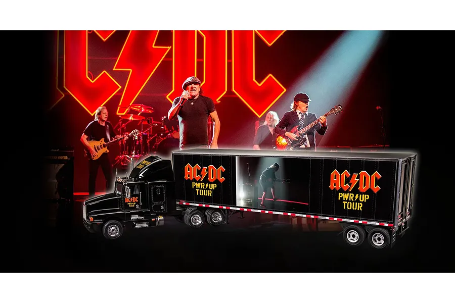 A 1/32 scale model of an AC/DC Power Up Tour semi-truck, featuring black livery with band branding, superimposed over a concert stage background.