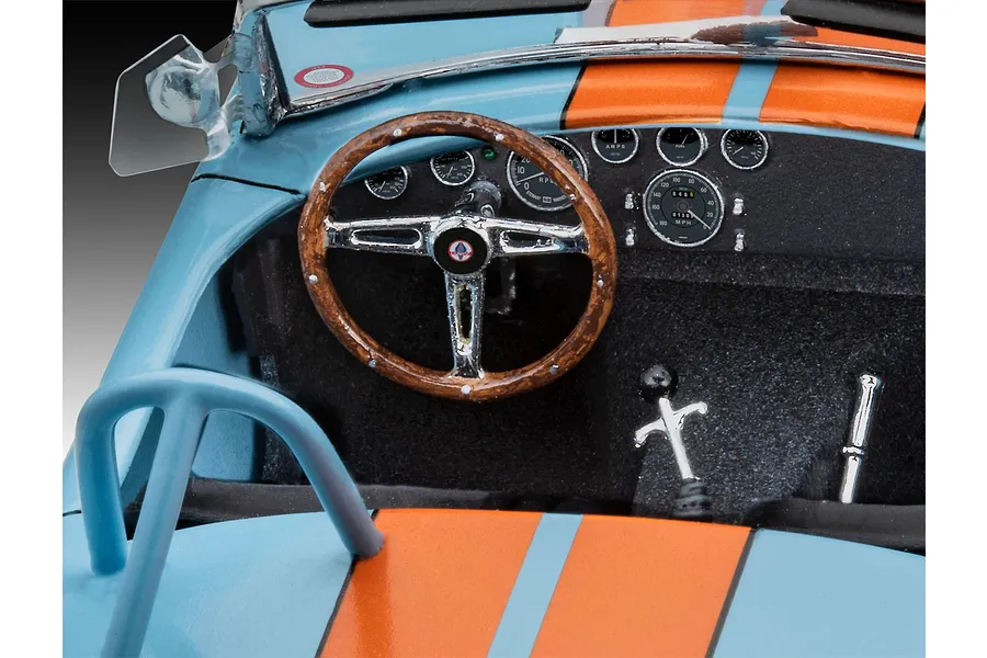 Close-up of the detailed interior of a 1/24 scale Shelby Cobra model car, showing the dashboard, steering wheel, and gear shifter.