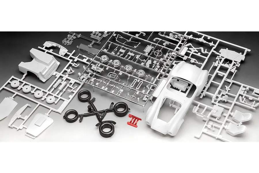 Unassembled plastic model kit parts for a 1/24 scale Shelby Cobra 427, including white body shell, chrome-plated parts, black tires, and red clear parts.