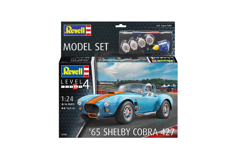 Revell 1/24 scale '65 Shelby Cobra 427 model kit box featuring a light blue race car with orange stripes on a track, including paints and glue.