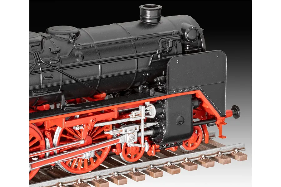 A close-up side view of a Revell 1/87 scale model steam locomotive in black and red, sitting on a detailed model railway track.